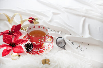 Christmas morning on white table. Side View of Christmas Tea Cup with Tea Strainer. Christmas Drink with Copy Space.