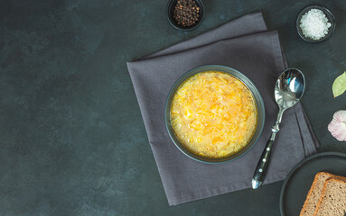 Chicken soup on black bowl on dark black stone table.