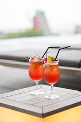 Singapore Sling Cocktails on Pool Side. Red Cocktail on Wooden Table. Asian inspired cocktail, Singapore cocktail against skyline.