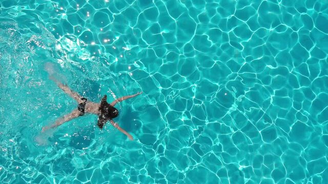 aerial view of young woman swimming breaststroke in the pool