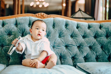 Fototapeta premium Asian baby sitting on sofa, summer fashion concept