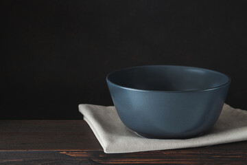 Empty bowl plate on wooden table over dark brown background