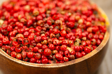 red peppercorn seeds in wooden plate