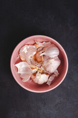 Raw garlic with segments scattered on black stone background