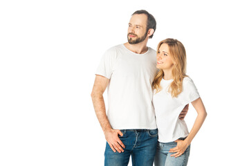 cheerful adult couple in white t-shirts embracing and looking away isolated on white