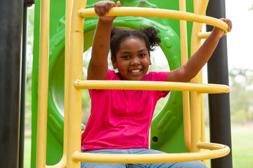 Cute Afro little girl with curly hair playing at the playground in the garden