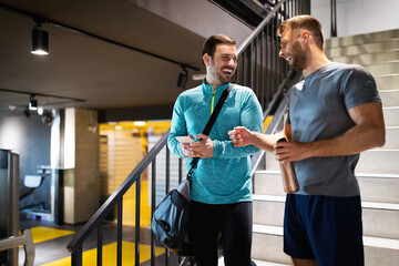 Sport, fitness, friends, lifestyle concept. Smiling men friends talking after workout in gym