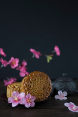 Traditional Baked Mooncake on Dark Background. Mooncakes with Sakura Flowers. Mooncake side view with Copy Space.