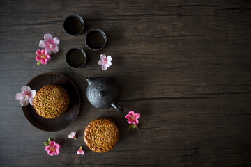 Mooncake flatlay on wooden table. Traditional Baked Mooncake on Dark Background. Mooncakes with Sakura Flowers. 