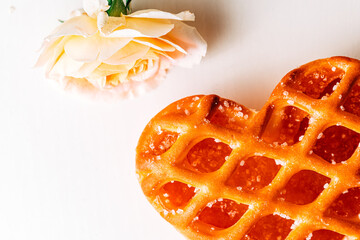 Heart shaped cookie with jam and witha fine pink roseson a white background. heart-shaped cake on a...