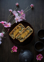 Obraz na płótnie Canvas Mooncake flatlay on wooden table. Traditional Baked Mooncake on Dark Background. Mooncakes with Sakura Flowers. 