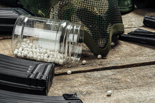 Close up of airsoft gun magazine and airsoft balls on wooden background