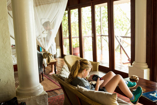 12 year old girl looking at smart phone in a hotel room, Botswana