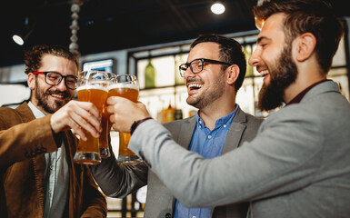 Leisure, friendship pub concept. Happy male friends drinking beer and clinking glasses at bar or pub