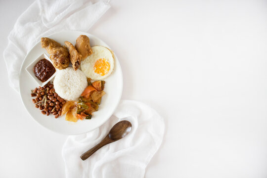 Nasi Lemak Flatlay On White Table. Singapore Food, Malaysian Food Called Nasi Lemak Or Coconut Rice, Shot Top Down. Nasi Lemak With Copy Space. 