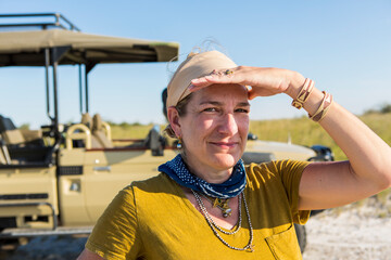 Adult woman shading her eyes from the sun, smiling.