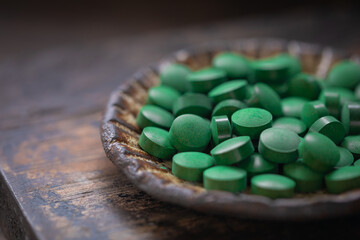 Chlorella or spirullina pills on a vintage plate, selective focus