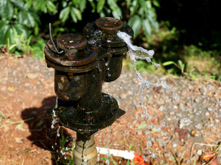 Old public water supply pipe leaking on the road side