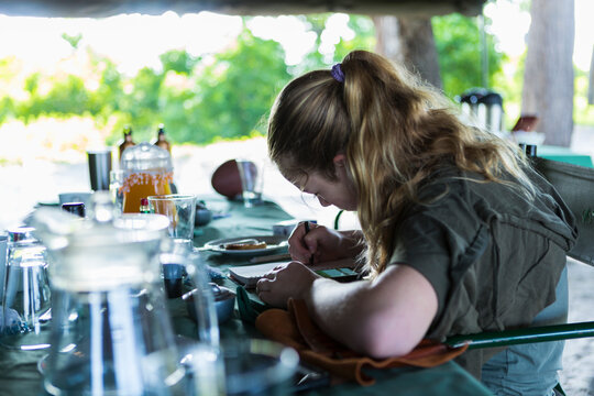Thirteen year old girl writing in her journal, tented camp, Botswana