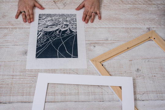 A person framing a lino cut into a border and picture frame.