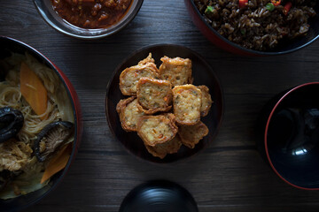 Singapore Peranakan Food Flat Lay. Peranakan Food on Wooden Table. Ngoh Hiang, Asian Fried Prawn Roll with Beancurd Skin, Chap Chye, Chili, Peranakan Fried Rice.
