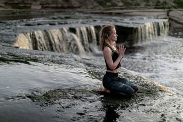 Blonde young woman in sportswear practicing breathing yoga outdoors in harmony with nature. Fitness...