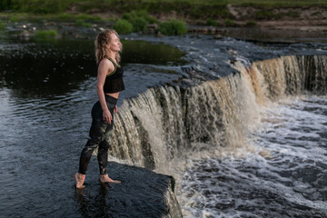 Blonde young woman in sportswear practicing breathing yoga outdoors in harmony with nature. Fitness...