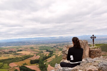 Fototapeta na wymiar Woman enjoying a moment of inspiration, meditation and fresh air from the top of the Clavijo castle, fields of cultivation in the background.