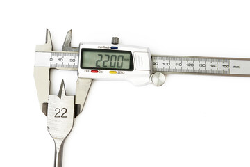 El calibrador digital toma medidas milimétricas de una broca para madera, aislado en blanco © Manueltrinidad