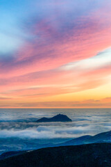 Fototapeta na wymiar Sunset from a view of Mountain Peak above Clouds