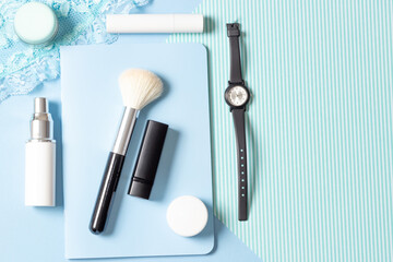 Women's cosmetics and accessories on a blue striped background: perfume, cream, lipstick, makeup brush. Fashion and Beauty Concept