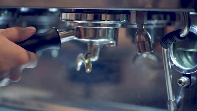 Coffee machine making espresso barista removing portafilter from professional coffee machine. Coffee tamper make coffee in coffee shop or cafe