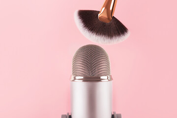 A makeup brush and a professional microphone on pink background. Making ASMR sounds.Trigger sounds...