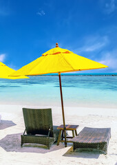 two chairs with Yellow umbrella on a sand beach