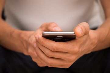 Close up, macro. A man sits and uses a smartphone.