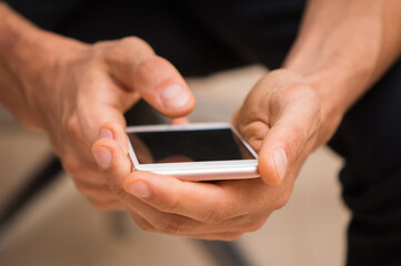 Close up, macro. Someone holds a smartphone in his hands and types a message.