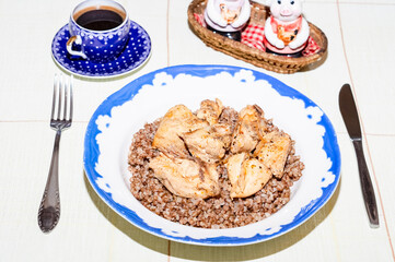 lunch or dinner of a bachelor. Plate with buckwheat and chicken meat on a round table covered with a tablecloth. meager lonely man dinner. blue and white porcelain cup and plate on the table