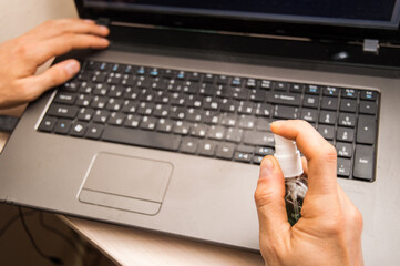 Close up. Male hand disinfect the laptop keyboard.