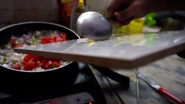 Man frying onions, tomatoes and other spieces