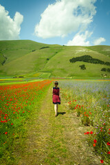 Fototapeta na wymiar girl walks among colorful flowers in Umbria when it's flowering time - relaxing journey into Italian nature