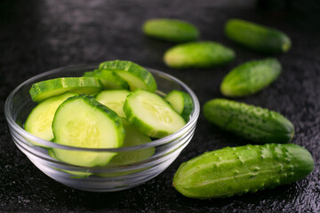 Sliced ​​cucumber in a plate on a black background.
Close-up.