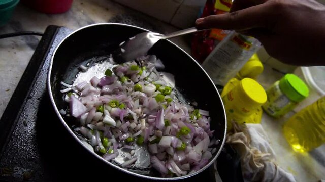 Man frying onions, tomatoes and other spieces