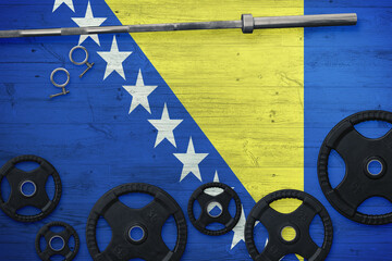 Bosnia Herzegovina gym concept. Top view of heavy weight plates with iron bar on national background.