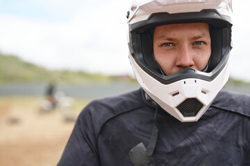 Portrait of serious young male motorcyclist in white helmet at off-road track © pressmaster