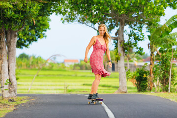 Young woman riding on skateboard. Happy woman have a fun on empty road. Active family lifestyle, outdoor recreational activities on summer holidays on tropical island.