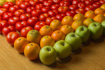 A group of apples, tomatoes, and oranges on a wooden table.