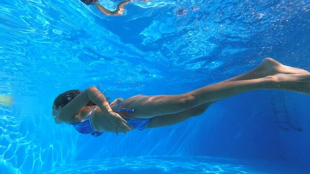 young woman swimming underwater rising to the surface and kissing her boyfriend