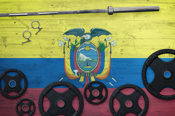 Ecuador gym concept. Top view of heavy weight plates with iron bar on national background.