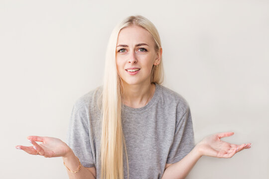 Portrait of magnificent lovely adorable gorgeous stylish nice confused girl in casual white t-shirt, showing uncertain gesture, isolated over beige background