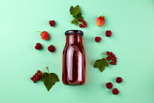 Summer refreshing drink made from fresh red berries: compote of raspberries, strawberries and red currant on a green background. Top view.